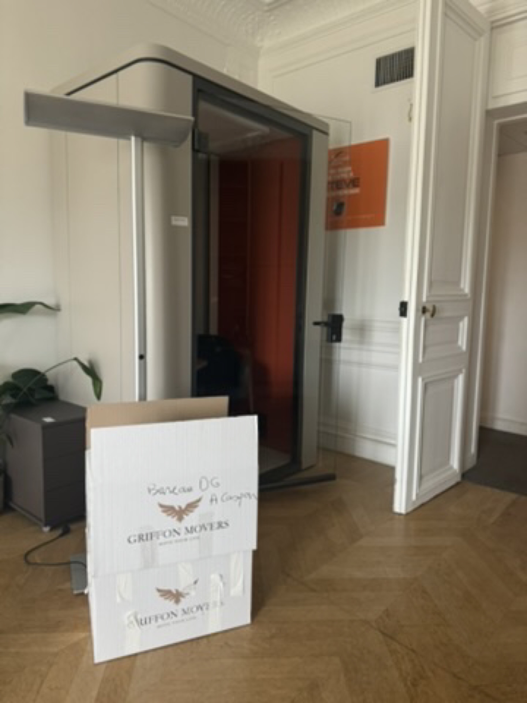 Cabine acoustique de bureau et cartons signés Griffon Movers en cours de transfert d'un siège social parisien